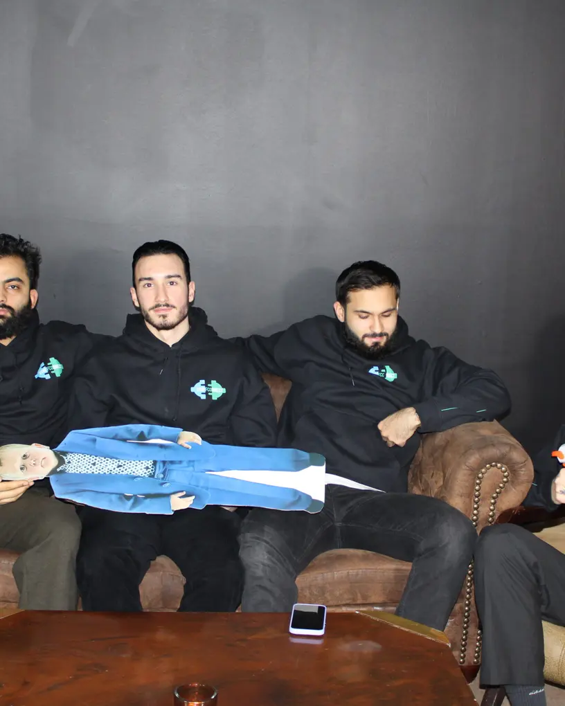 Crew in Marken-Hoodies mit Requisiten auf Sofas, Drehpause