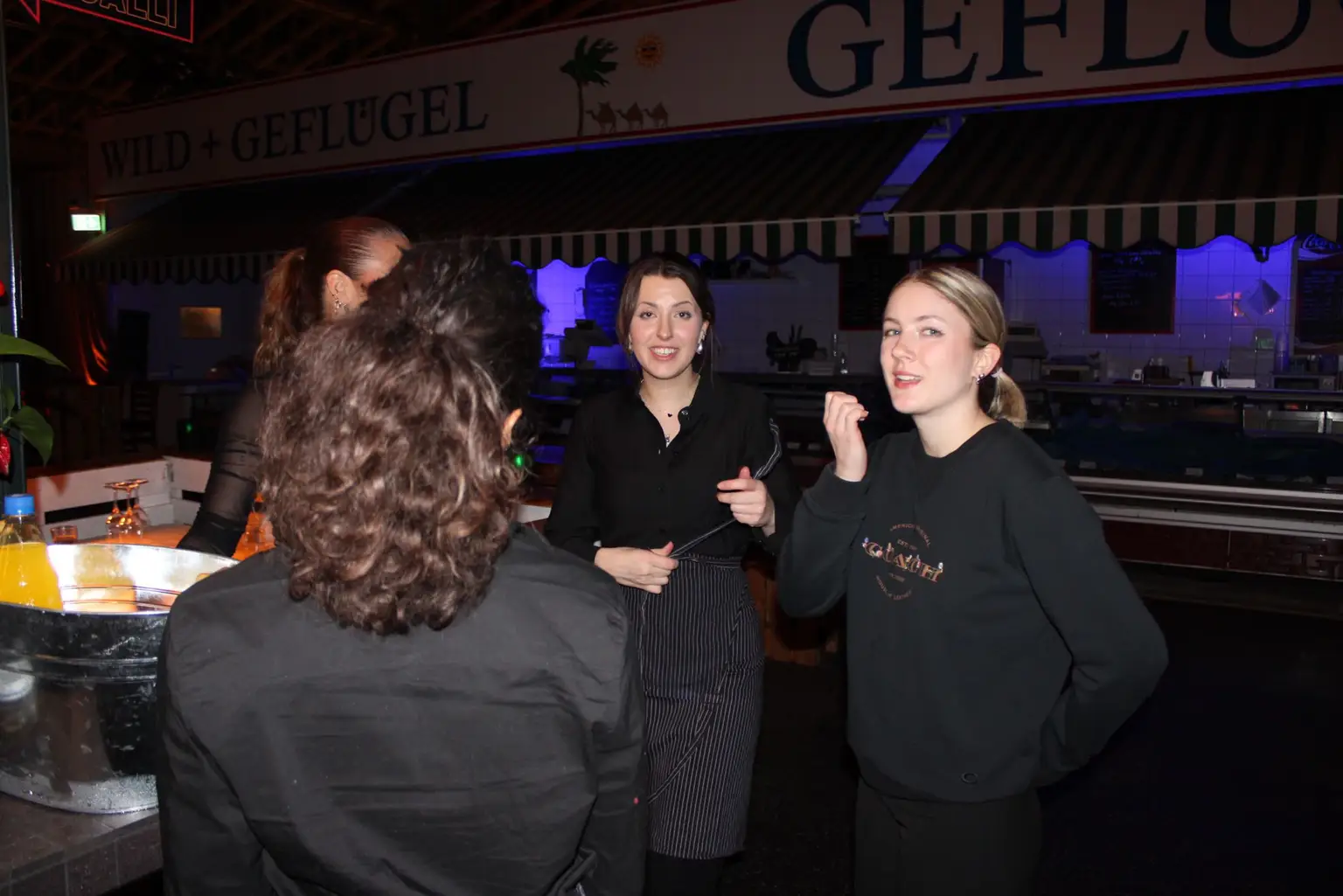 Team in Marken-Hoodies im Abendbetrieb einer Markthalle