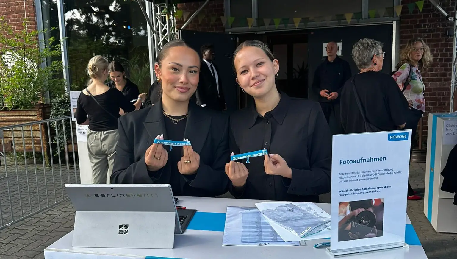 Zwei Hostessen am Check-in-Tisch mit Laptop und Tickets im Freien