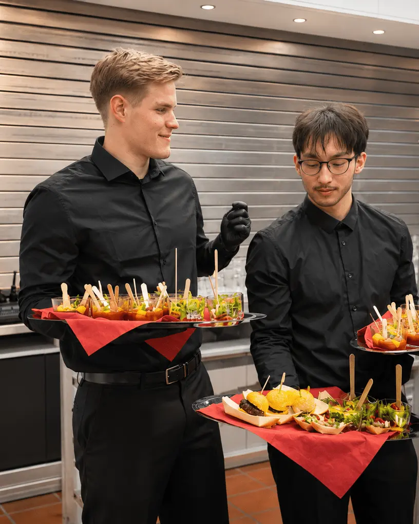 Kellner mit Flying-Food-Tablett zwischen Gästen