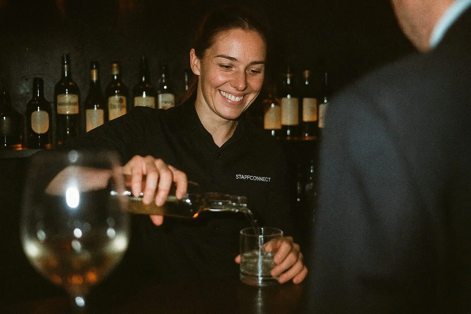 Barkraft schenkt an einer Abendbar Weißwein ein