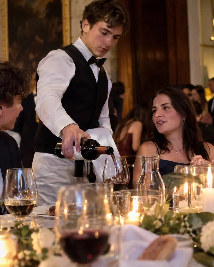 Kellner mit Weste und Fliege schenkt beim Galadinner im historischen Saal Rotwein nach – Personal für das Firmenjubiläum