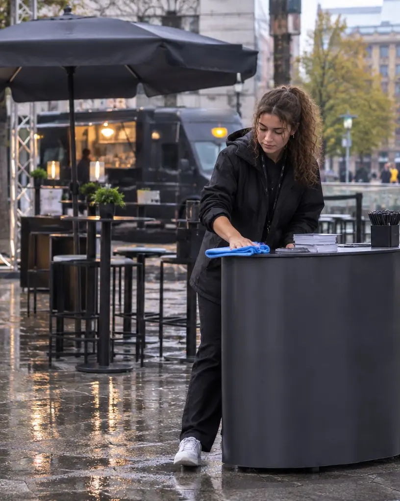 Promoter wipes the rain off the counter of her promotion stand